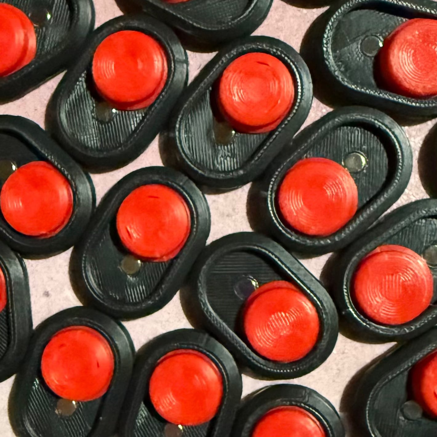 Multiple Snappy™ Dragon Eye - Fidget Keyboard Toys arranged in a pattern, showcasing red clicky buttons on black bases for tactile fun.