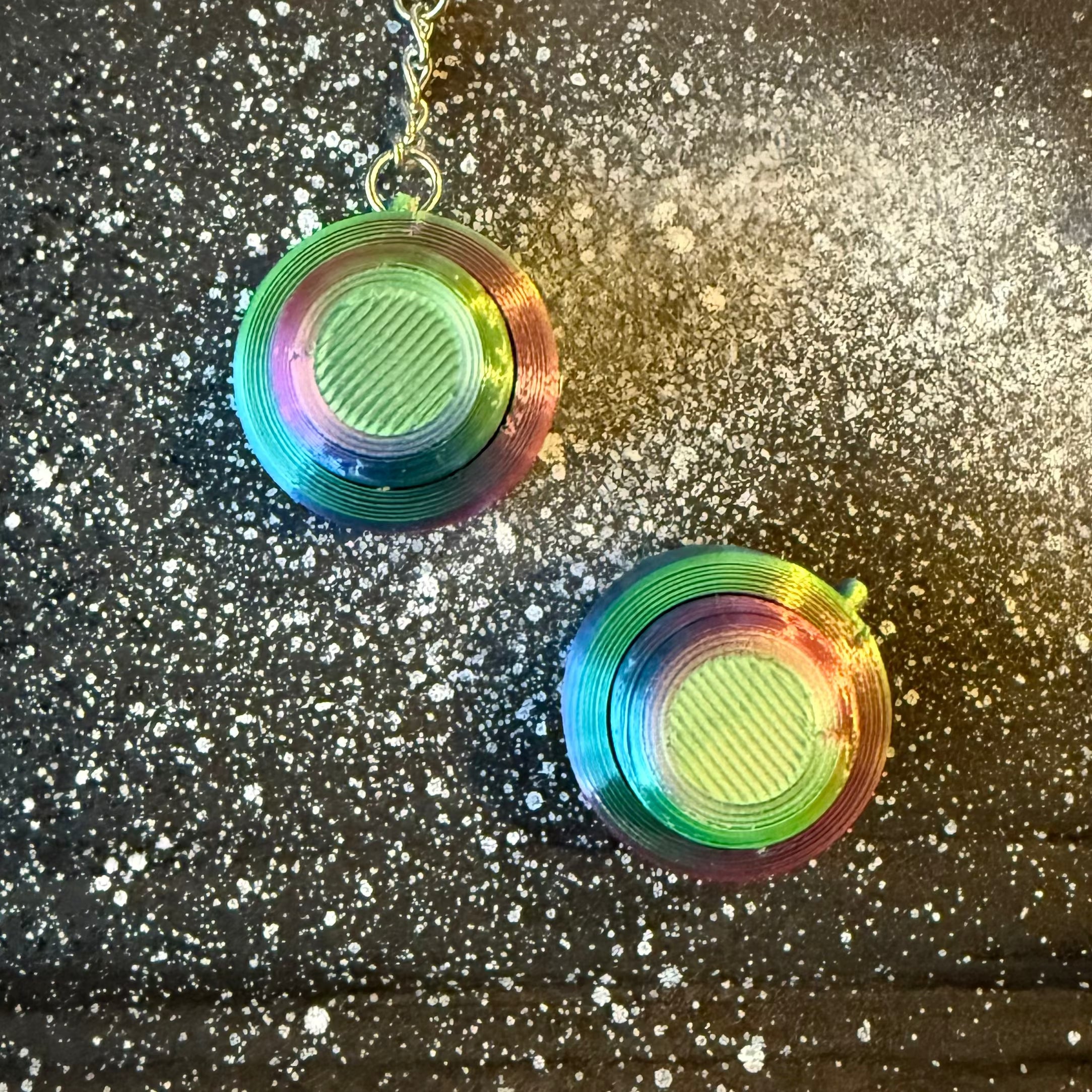 Snappy™ Northern Lights Keychains with round aurora-colored tops and chain attachment, displayed on a cosmic-themed surface. Perfect for fidgeting fun.