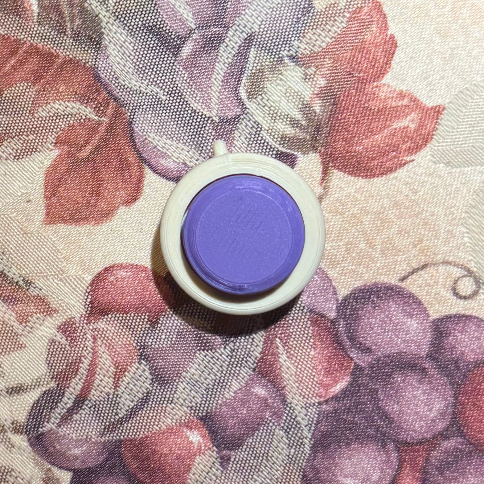Snappy™ Hidden Gem Clicker Classic style with a purple button, ideal for enhancing focus and creativity. Compact executive fidget toy on floral background.