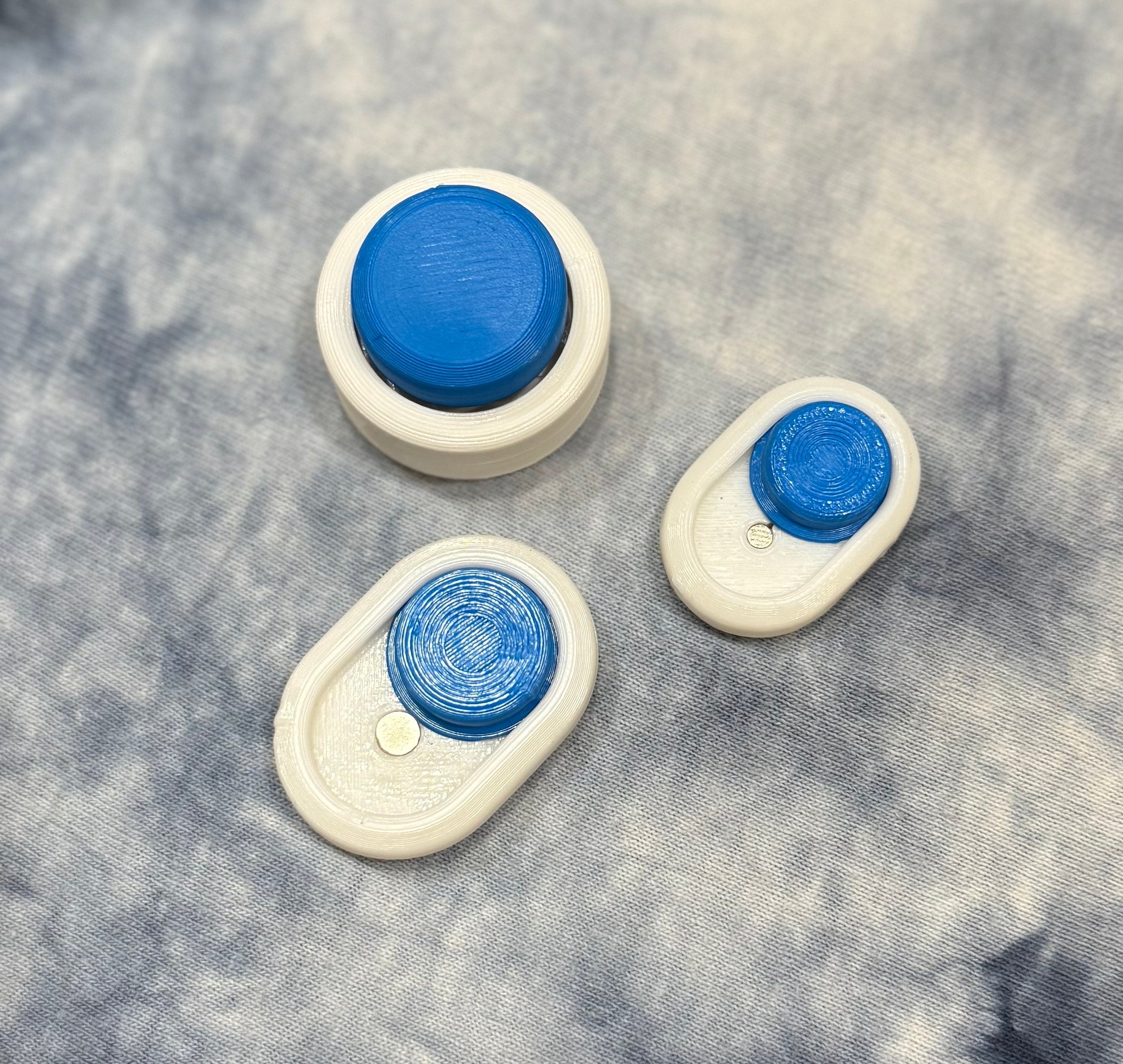 Snow Cap Keychain set in white and blue with compact, minimal design. Includes two small keychain versions and one larger desktop model.